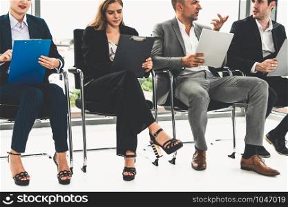 Businesswomen and businessmen holding resume CV folder while waiting on chairs in office for job interview. Corporate business and human resources concept.