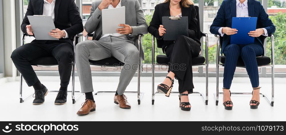 Businesswomen and businessmen holding resume CV folder while waiting on chairs in office for job interview. Corporate business and human resources concept.