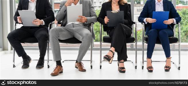 Businesswomen and businessmen holding resume CV folder while waiting on chairs in office for job interview. Corporate business and human resources concept.