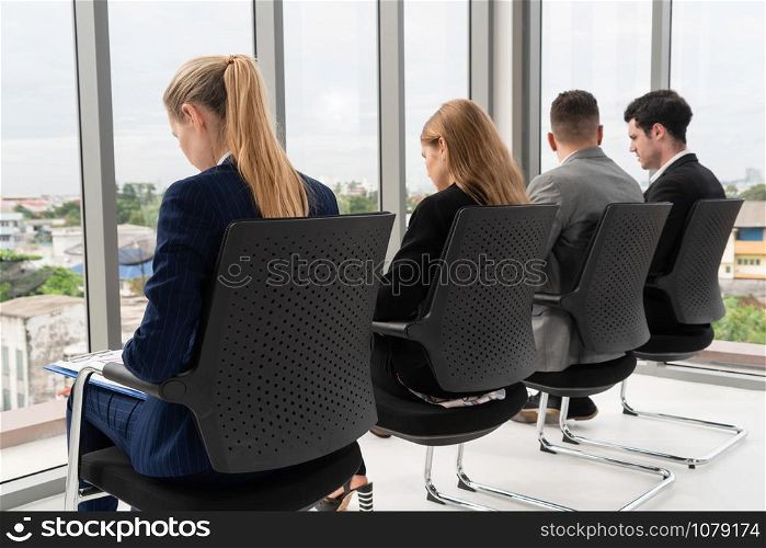 Businesswomen and businessmen waiting on chairs in office for job interview. Corporate business and human resources concept.