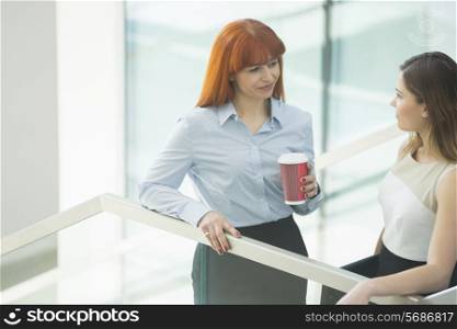 Businesswomen conversing while having coffee in office