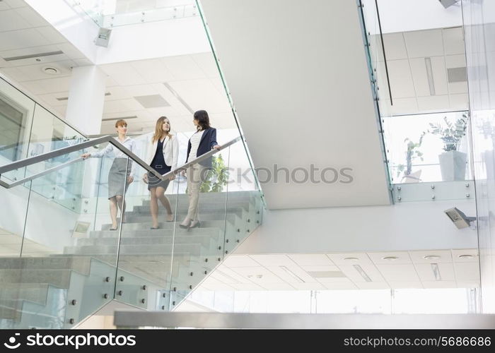 Businesswomen conversing while moving down steps in office