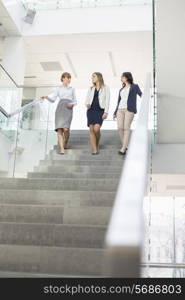 Businesswomen conversing while moving down steps in office