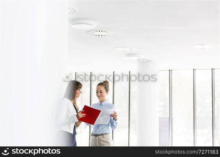Businesswomen discussing over document while standing at office