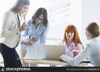 Businesswomen discussing over documents at table in office