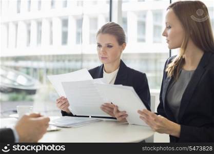 Businesswomen discussing over documents in office cafeteria