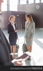 Businesswomen discussing plans while walking with their suitcase in airport