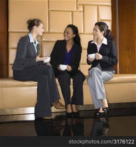 Businesswomen drinking coffee and conversing.
