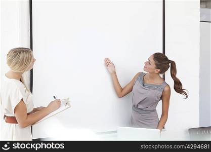 Businesswomen examining screen in office