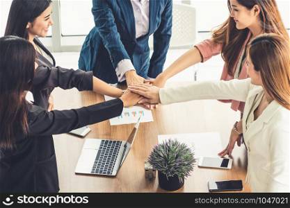 Businesswomen joining hands in group meeting at modern office room showing teamwork, support and unity in work and business. Female power and femininity concept.
