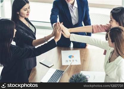 Businesswomen joining hands in group meeting at modern office room showing teamwork, support and unity in work and business. Female power and femininity concept.
