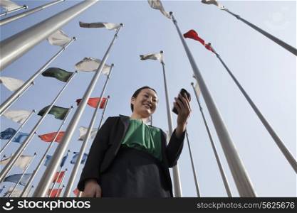Businesswomen looking at mobile phone with flags in background.