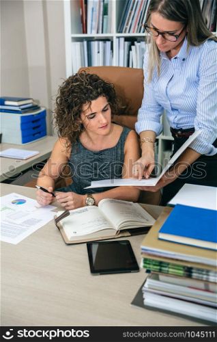 Businesswomen looking documents in folder in the office. Female business leadership concept.. Businesswomen looking documents in folder in the office