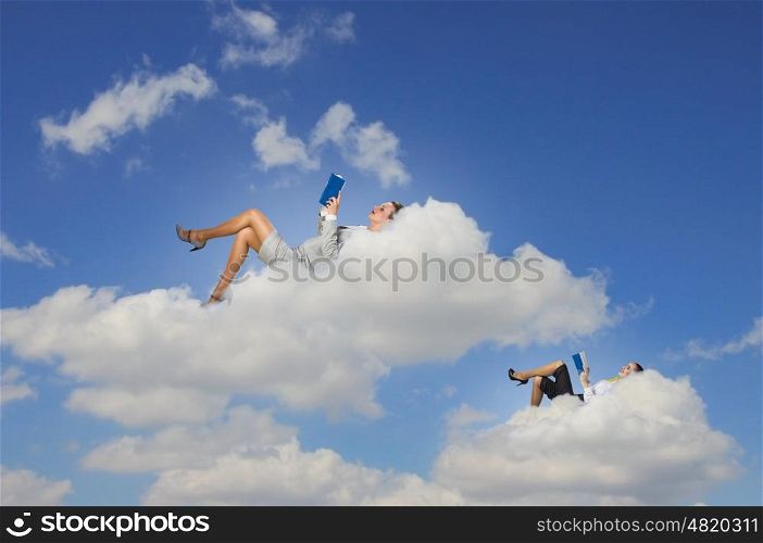 Businesswomen lying on clouds. Image of businesswomen lying on clouds with book
