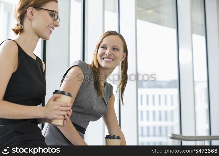 Businesswomen with disposable coffee cups at office