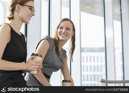 Businesswomen with disposable coffee cups at office