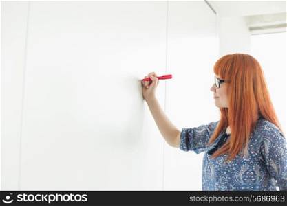 Businesswomen writing on whiteboard in creative office
