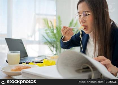 Busy and tired businesswoman eating spaghetti for lunch at the Desk office and working to deliver financial statements to a boss. Overworked and unhealthy for ready meals, burnout concept.