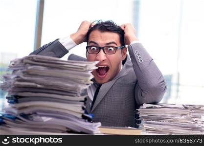 Busy angry businessman with heaps of paper