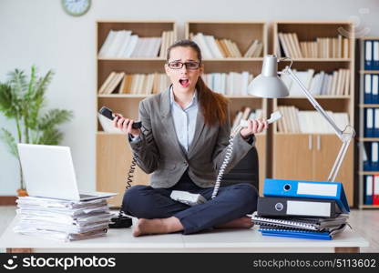 Busy angry businesswoman sitting on the desk in office