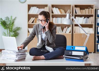 Busy angry businesswoman sitting on the desk in office