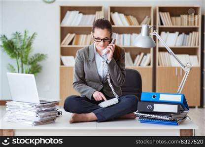 Busy angry businesswoman sitting on the desk in office