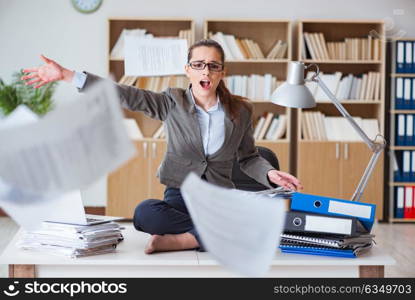 Busy angry businesswoman sitting on the desk in office