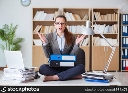 Busy angry businesswoman sitting on the desk in office