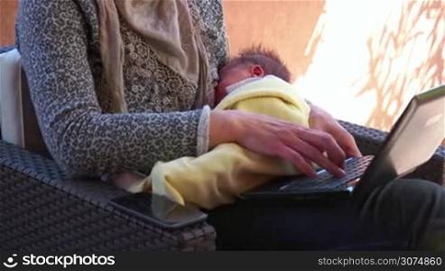 Busy business woman breastfeeding newborn baby. Multitasking mom working, nursing infant. Mother holding child at home, typing on laptop computer. Businesswoman nursing son. People, family, maternity
