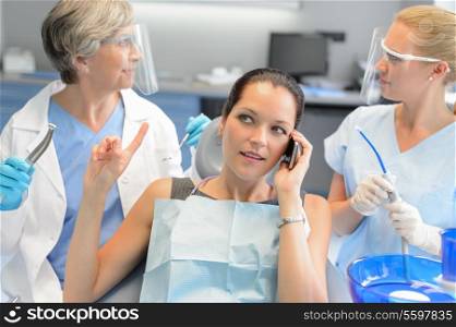 Busy businesswoman at dental surgery calling on phone dentists waiting