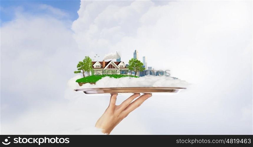 Busy city or countryside calm life. Hand holding metal tray with model of modern city and suburban house