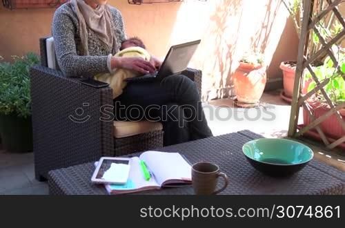 Busy female manager feeding newborn baby. Multitasking mom working, nursing infant. Mother holding child at home, typing on pc, talking on phone. Happy business woman nursing son. Parenting, maternity