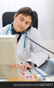 Busy medical speaking phone and working on computer