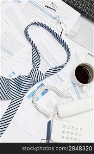 Busy office desk tie lying on paper charts business meeting