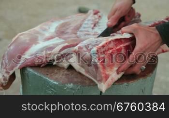 Butcher cutting fresh pork meat, close-up