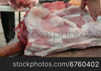 Butcher cutting fresh pork meat, close-up