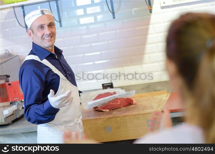 butcher cutting meat for client