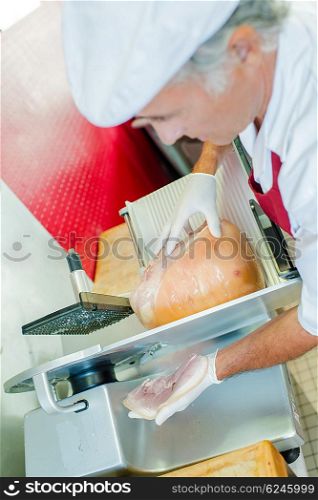 Butcher slicing some ham for a customer