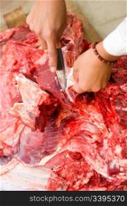 butchers hands with knife cutting fresh beef