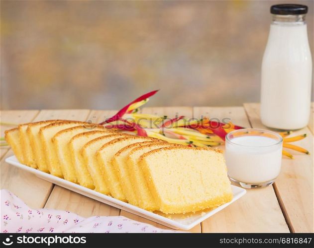 Butter cake and bottle with glass of milk on white wooden table