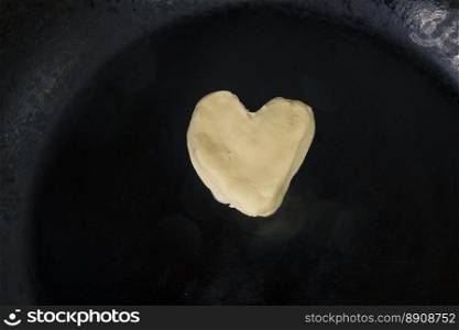 Butter in shape of heart on hot pan - Close up top view 