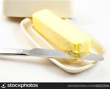 butter on a white butterdish with knife , close up