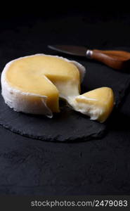 Butter soft creamy sheep cheese from Seia region Portugal on black slate board, with one piece cut and cheese melting
