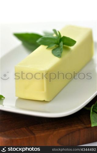 Butter stick on a white dish with basil leaves