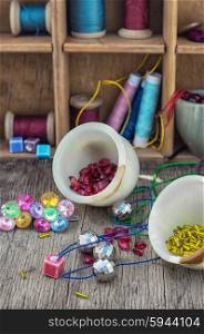 Buttons,threads and beads on wooden countertop on the background box with accessories