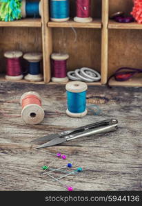 Buttons,threads and beads on wooden countertop on the background box with accessories