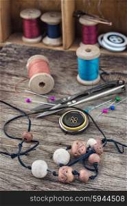 Buttons,threads and beads on wooden countertop on the background box with accessories