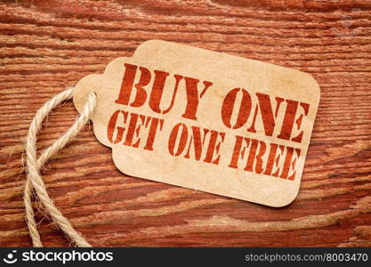 buy one get one free sale sign - a paper price tag against rustic red painted barn wood - shopping concept