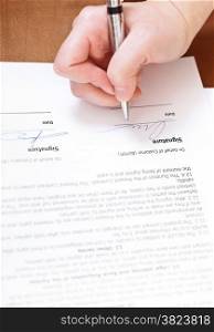 buyer signs an agreement by silver pen on table