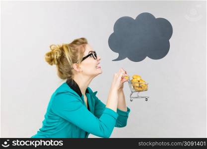 Buying gluten food products concept. Bussines woman holding shopping cart trolley with sweet bun, black thinking or speech bubble next to her.. Bussines woman holding shopping cart with sweet bun